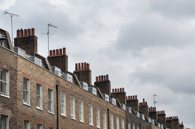 Chimney houses in London against cloudy sky.