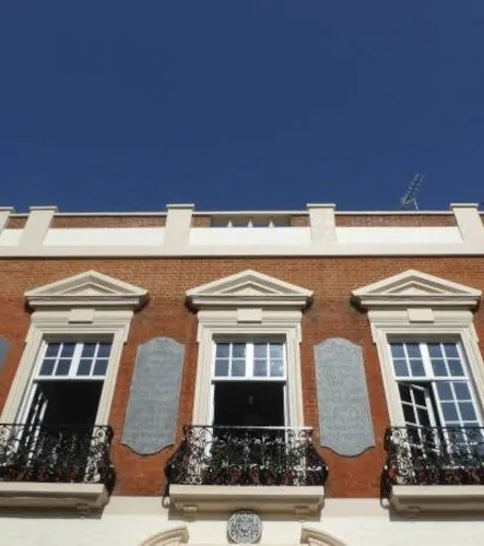 Brick building with ornate balconies and decorative window frames under a clear blue sky.
